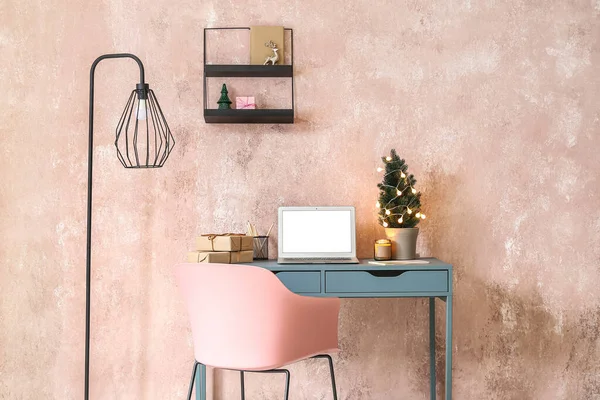 ノートパソコン クリスマスツリーとピンクの壁の近くの贈り物を持つ職場 — ストック写真