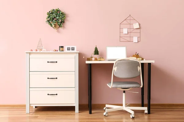 オフィスのピンクの壁の近くのラップトップとクリスマスプレゼント付きの職場 — ストック写真