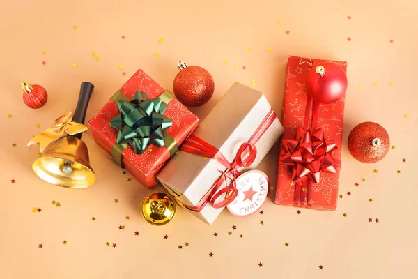 Geschenke Mit Weihnachtsglocke Und Kugeln Auf Beigem Hintergrund — Stockfoto