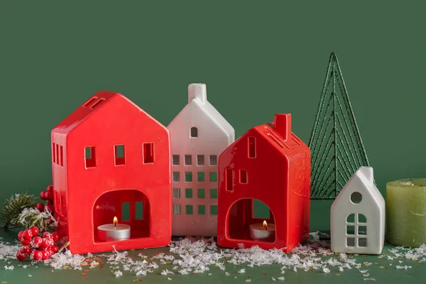 stock image House shaped candle holders with snow on green background