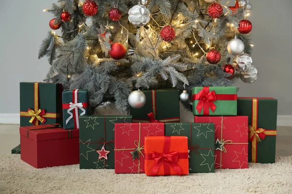 灰色の壁の近くのクリスマスツリーの下の贈り物 — ストック写真
