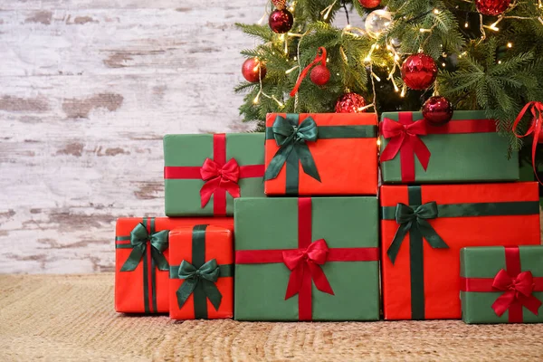Cadeaus Onder Gloeiende Kerstboom Bij Grunge Muur — Stockfoto