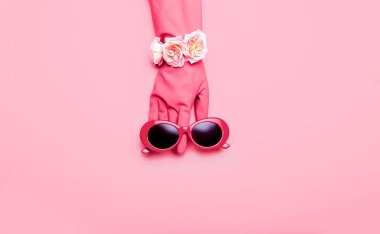 Lastik eldivenli şık güneş gözlükleri ve pembe arka planda gül çiçekleri. Viva Magenta - Yeni yılın rengi 2023