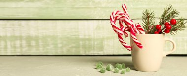 Çubuklu şekerler ve ahşap zemin üzerinde Noel süslemeleri olan bardakta metin için yer var.