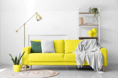 Sarı kanepeli ve raf üniteli aydınlık oturma odasının içi.