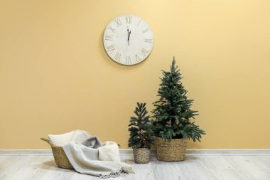 Ekoseli sepet, Noel ağaçları ve bej duvarda asılı büyük bir saat.