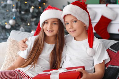 Noel hediyeli pijamalı küçük çocuklar evde oturuyor.