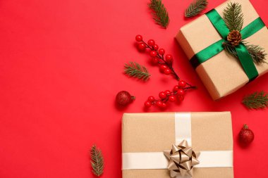 Kırmızı arka planda köknar dalları, toplar ve viburnum olan Noel hediyesi kutuları