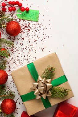 Beyaz arka planda köknar dalları, toplar ve pullarla Noel hediyesi
