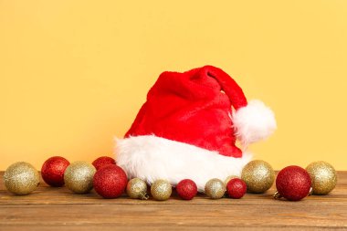 Noel Baba şapkası ve güzel Noel topları ahşap masanın üzerinde renk arka planına karşı