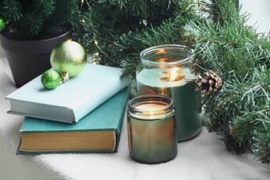Noel topları, mumlar ve pencere kenarında köknar dalları olan kitaplar, yakın plan