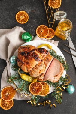Lezzetli jambon, kurutulmuş sitruslar ve karanlık masa üzerinde Noel dallarıyla dolu bir tabak.