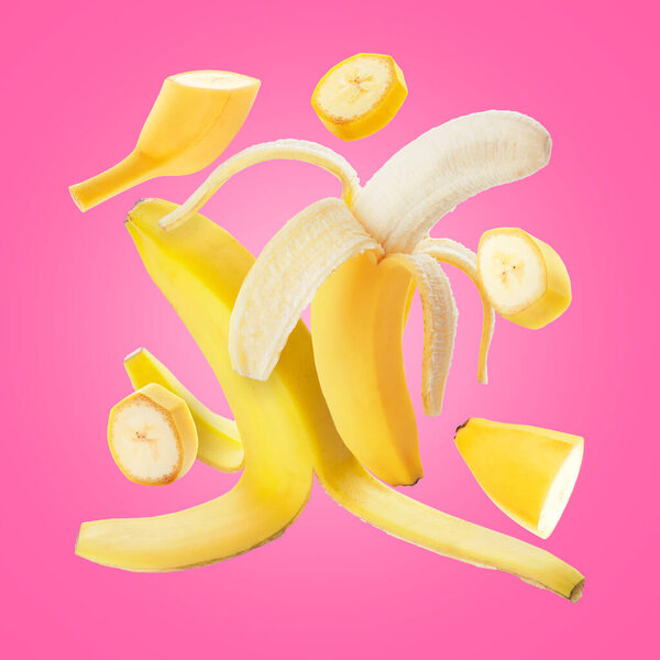 Летающие свежие бананы на розовом фоне
