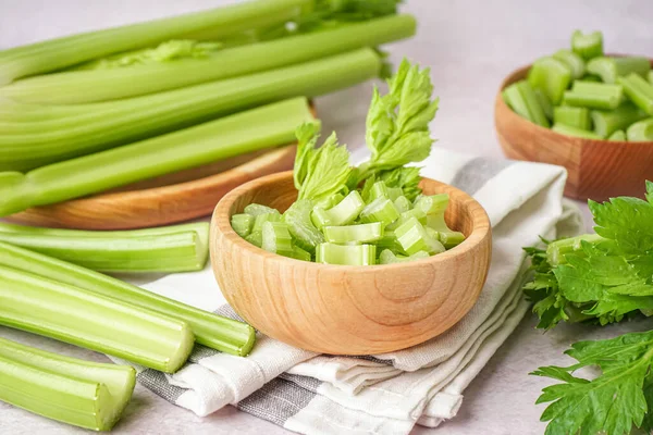 Wooden bowl with cut celery on table