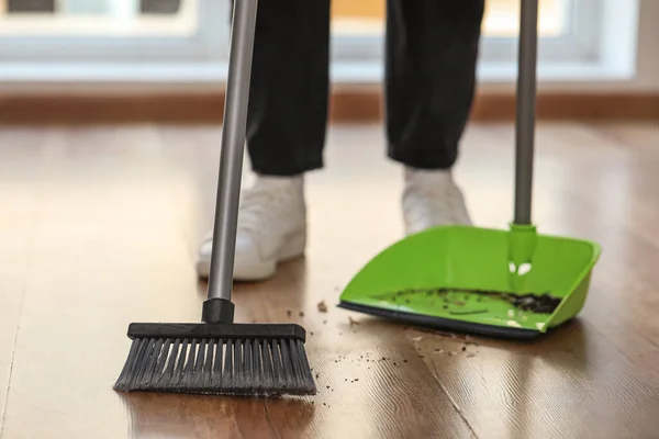Woman sweeping floor with broom and dustpan