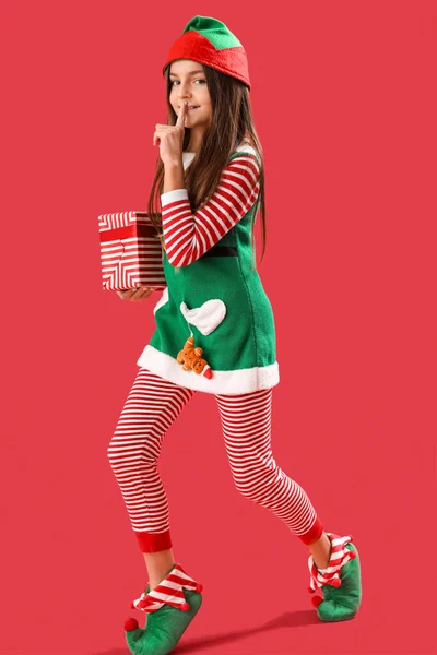 Kleines Mädchen Elfen Pyjama Mit Weihnachtsgeschenk Zeigt Schweigegegeste Auf Rotem — Stockfoto