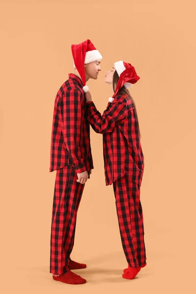 若いですカップルでサンタ帽子とパジャマでベージュ — ストック写真