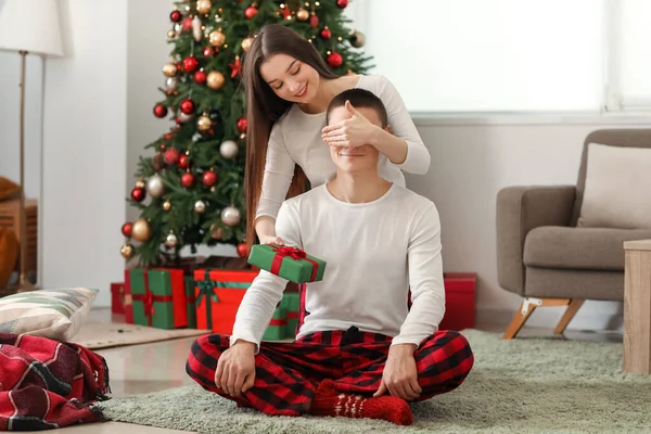 Jovem Mulher Surpreendendo Seu Namorado Com Presente Natal Casa — Fotografia de Stock