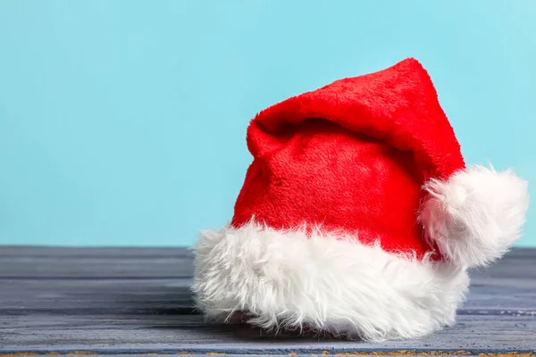 Weihnachtsmütze Auf Dunklem Holztisch Vor Farbigem Hintergrund — Stockfoto