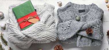 Noel hediyesi ve beyaz ahşap arka planda dekoru olan şık kazaklar.