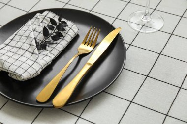 Beyaz kareli kumaş üzerinde bitki dalı olan zarif masa ayarı, yakın plan.