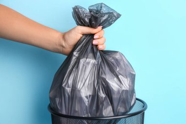 Woman taking garbage bag out of rubbish bin on color background, closeup clipart