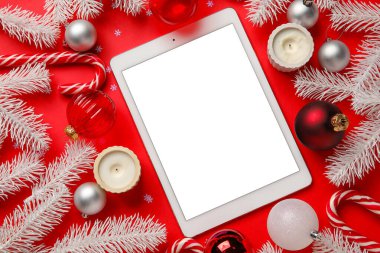 Kırmızı arka planda Noel dekoru olan boş bir tablet bilgisayar