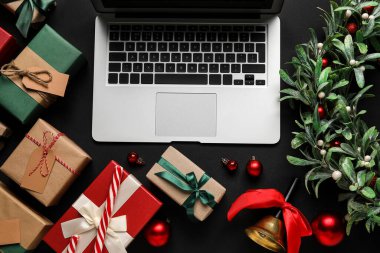 Noel dekorlu dizüstü bilgisayar ve siyah arka planda hediyeler