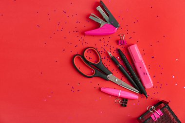 Kırmızı arkaplanda farklı kırtasiye malzemesi olan kompozisyon