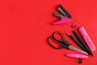 Kırmızı arkaplanda farklı kırtasiye malzemesi olan kompozisyon