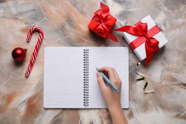 Boş defter, kalem, Noel hediyeleri ve grunge arkaplanda süslemeleri olan kadın eli