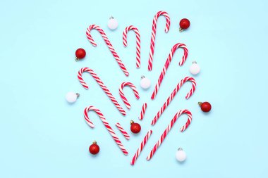 Lezzetli şeker kamışları ve renkli arkaplanda Noel topları olan kompozisyon