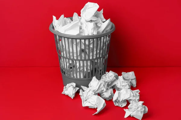 Office bin with crumpled paper on red background