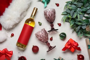 Gözlüklü bir şişe şarap, hediyeler, Noel Baba şapkası ve arka planda Noel topları.