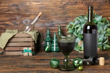 Koyu ahşap masada Noel topları olan bir kadeh şarap, yakın plan.