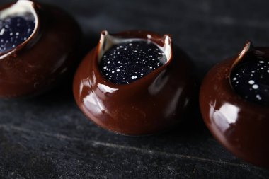 Koyu arkaplanda çikolatalı şekerler, yakın plan.