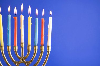 Hannukah kutlaması için mum yakan Menorah mavi arka planda, yakın plan