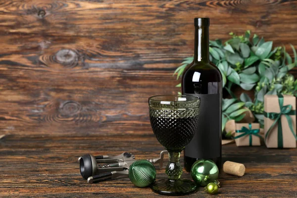 Bottle of wine with glass, opener and Christmas balls on dark wooden background