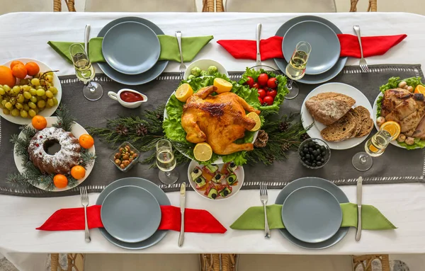 Christmas table setting with tasty meat and cake in dining room, top view