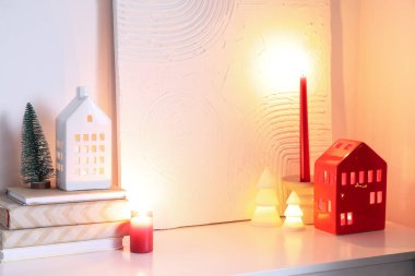 Kitaplı mumluklar, yılbaşı ağaçları ve raflardaki tablolar.