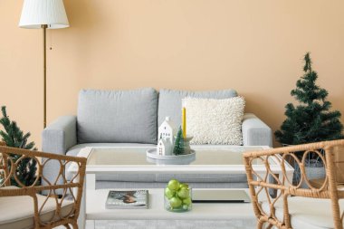 Oturma odasının içinde mum tutucuları, Noel ağaçları ve koltuklar var.