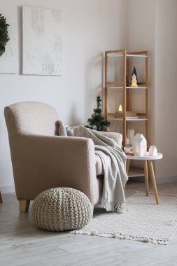 Oturma odasının içinde koltuk, mum tutacağı ve Noel ağacı var.