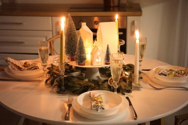 Geceleri mutfakta mum tutacakları ve köknar ağaçları olan bir Noel masası.