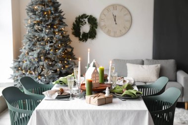 Noel sofrasında mum tutucuları, hediyeler ve yemek odasında köknar ağaçları.