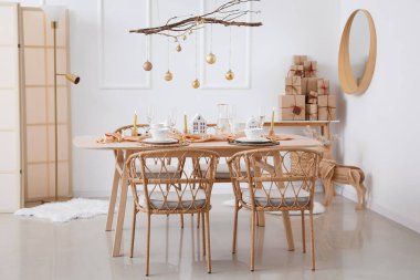 Yemek masası, ağaç dalları ve Noel topları olan ışık odasının içi.