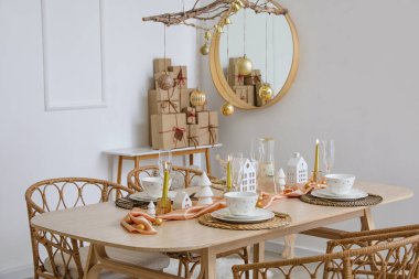 Yemek masası, ağaç dalları ve Noel topları olan ışık odasının içi.