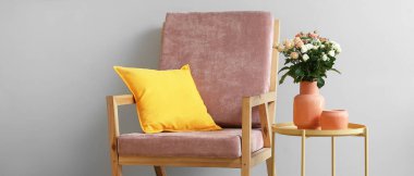 Masada bir buket güzel taze gül ve odada ışık duvarının yanında yastıklı rahat bir koltuk.