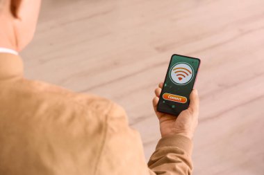 Cep telefonunda kablosuz ağ sembolü ve ışık arkaplanı üzerindeki bağlantı düğmesi olan adam