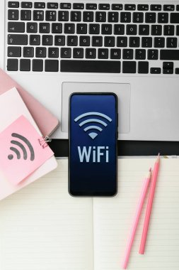 Wi-Fi sembollü kırtasiye malzemeleri, laptop ve cep telefonu, yakın plan.