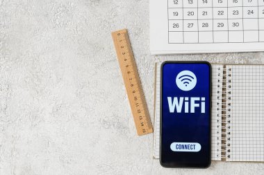 Takvim, kırtasiye malzemeleri ve WiFi sembollü cep telefonu, yakın plan